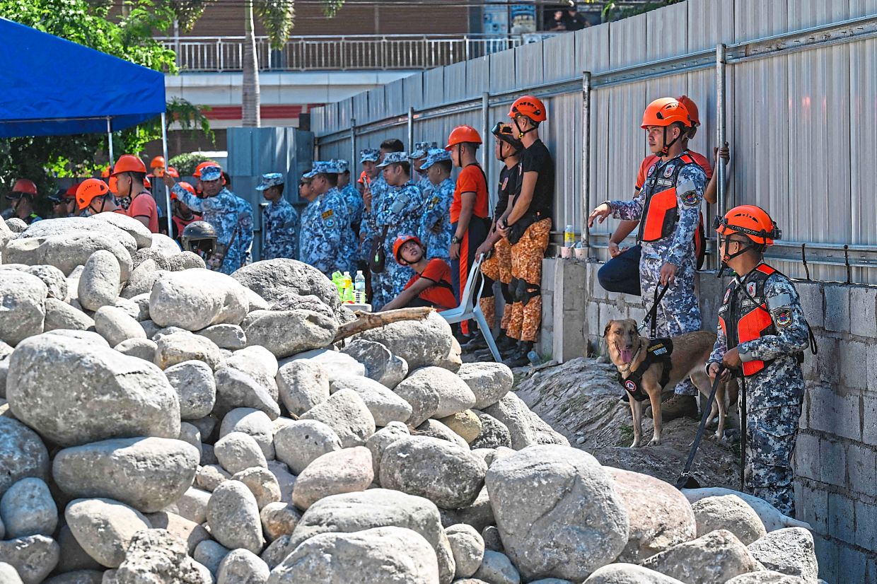 Emergency responders meeting for a briefing before fanning out for search-and-rescue operations at the site of a collapsed building. — AFP