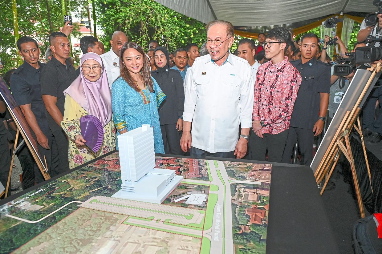 Resettlement project: Anwar together with his wife Datuk Seri Dr Wan Azizah Wan Ismail and Federal Territories Minister Hannah Yeoh taking a closer look at the plan of the permanent housing development to replace the Bukit Kiara longhouse. — IZZRAFIQ ALIAS/The Star