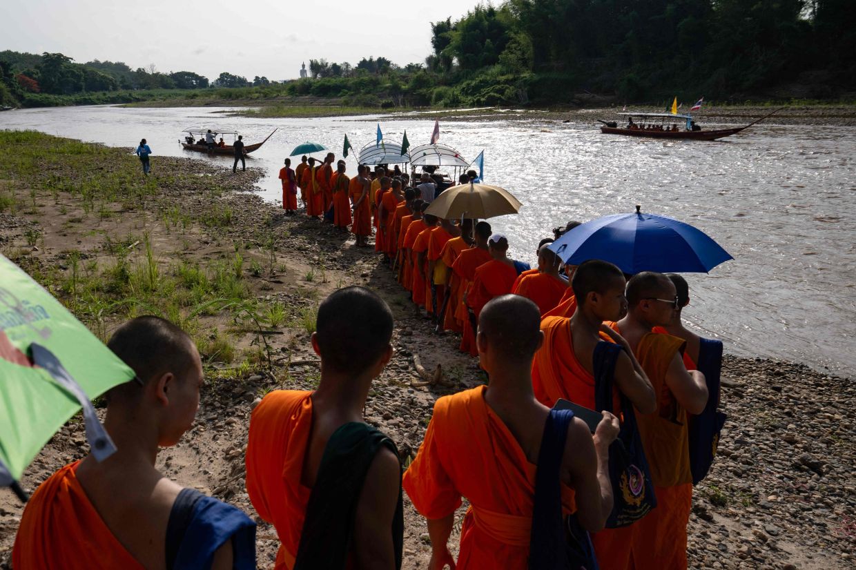 Buddhist monks taking part in a flotilla to highlight the toxic contamination of rivers affected by gold mining, near the northern Thai city of Chiang Rai. Thailand's pollution control department said in April it had found arsenic concentrations of up to 296 milligrams per kilogram of sediment near Chiang Saen -- more than nine times the level considered dangerous for aquatic life. -- Photo by Lillian SUWANRUMPHA / AFP