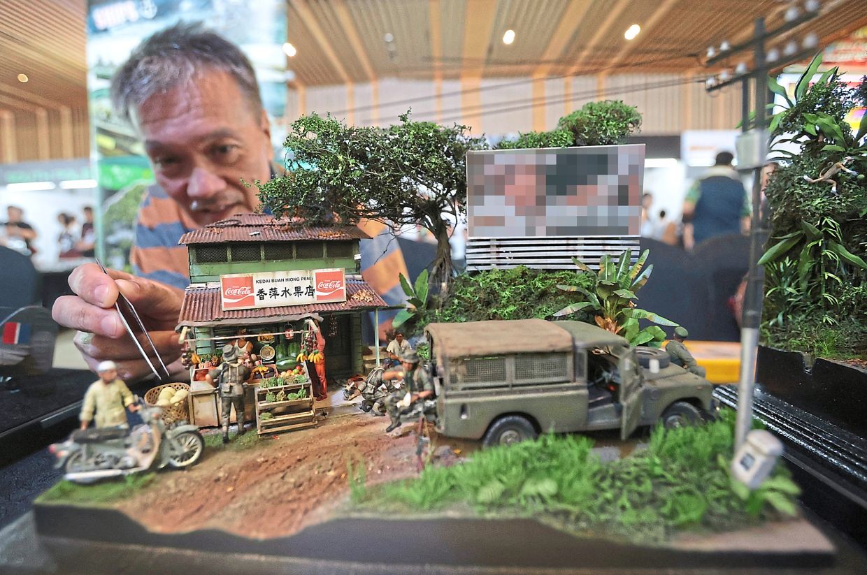 Foenander demonstrating how he crafts the tiny details on his dioramas.