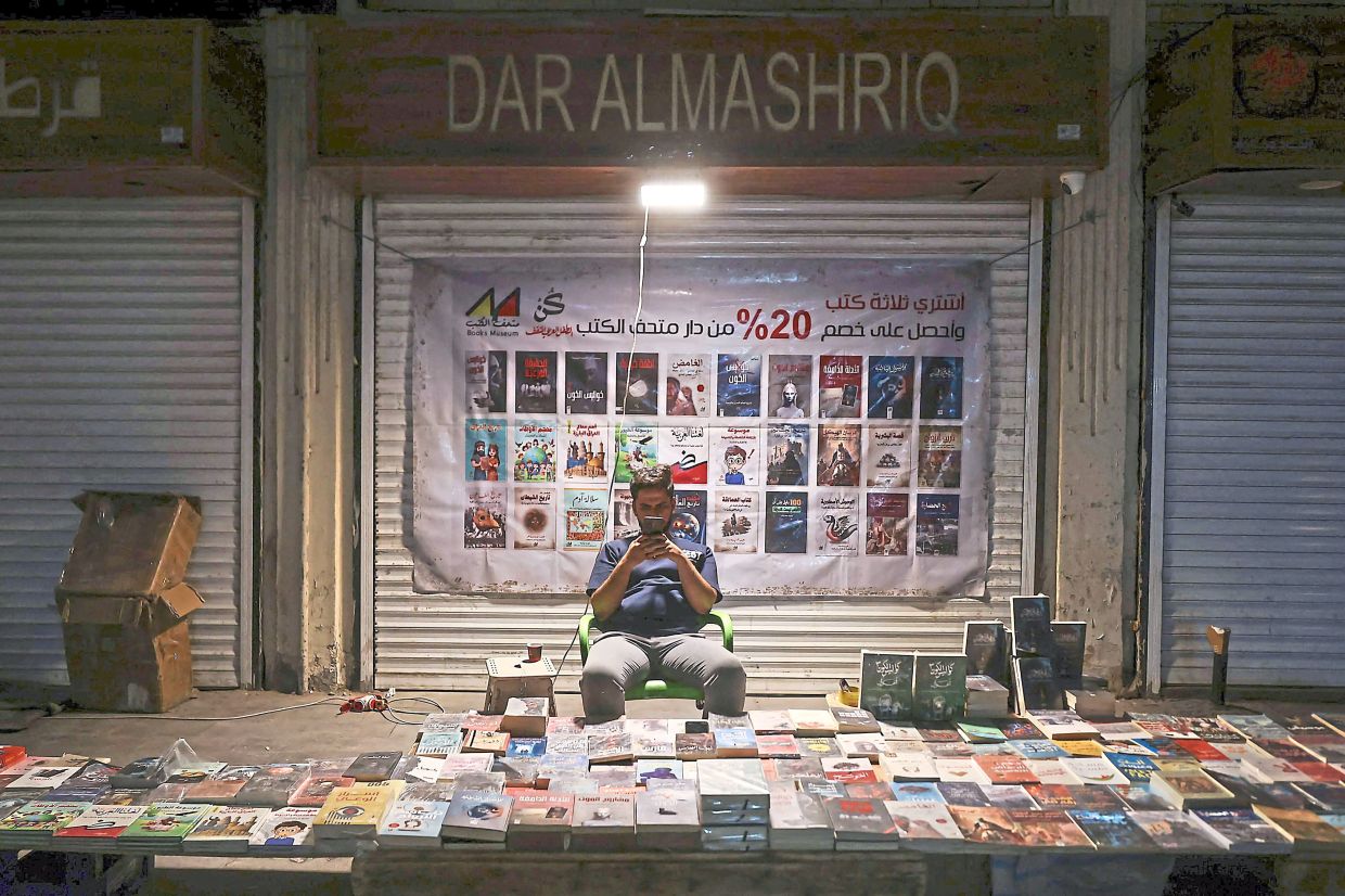 An Iraqi bookseller passes the time at his stall on Mutanabbi Street in Baghdad. Photo: AFP