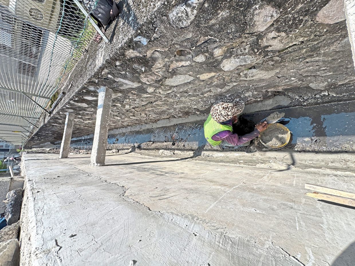 A contractor cementing a section of the perimeter drain wall in Jalan Perdana 4/1. — LOW BOON TAT/The Star