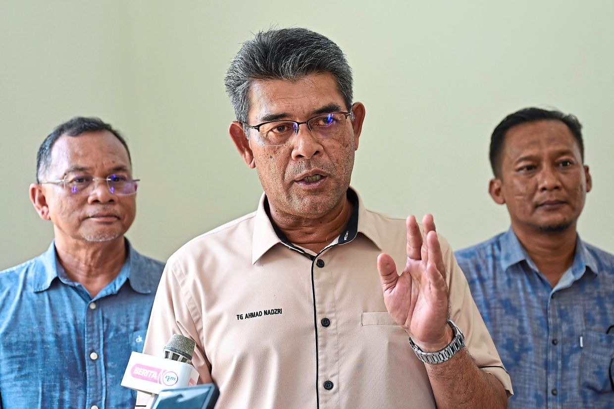 Tengku Ahmad Nadzri (centre) talking to reporters during the handover of houses programme in Chukai.