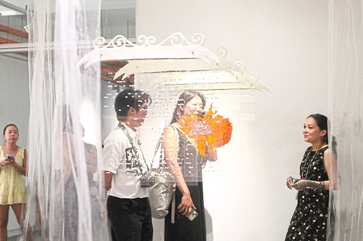 Bethany (right) talks to visitors about her artwork 'Asap',featuring four transparent acrylic panes and a video. Photo: The Star/M. Irsyad