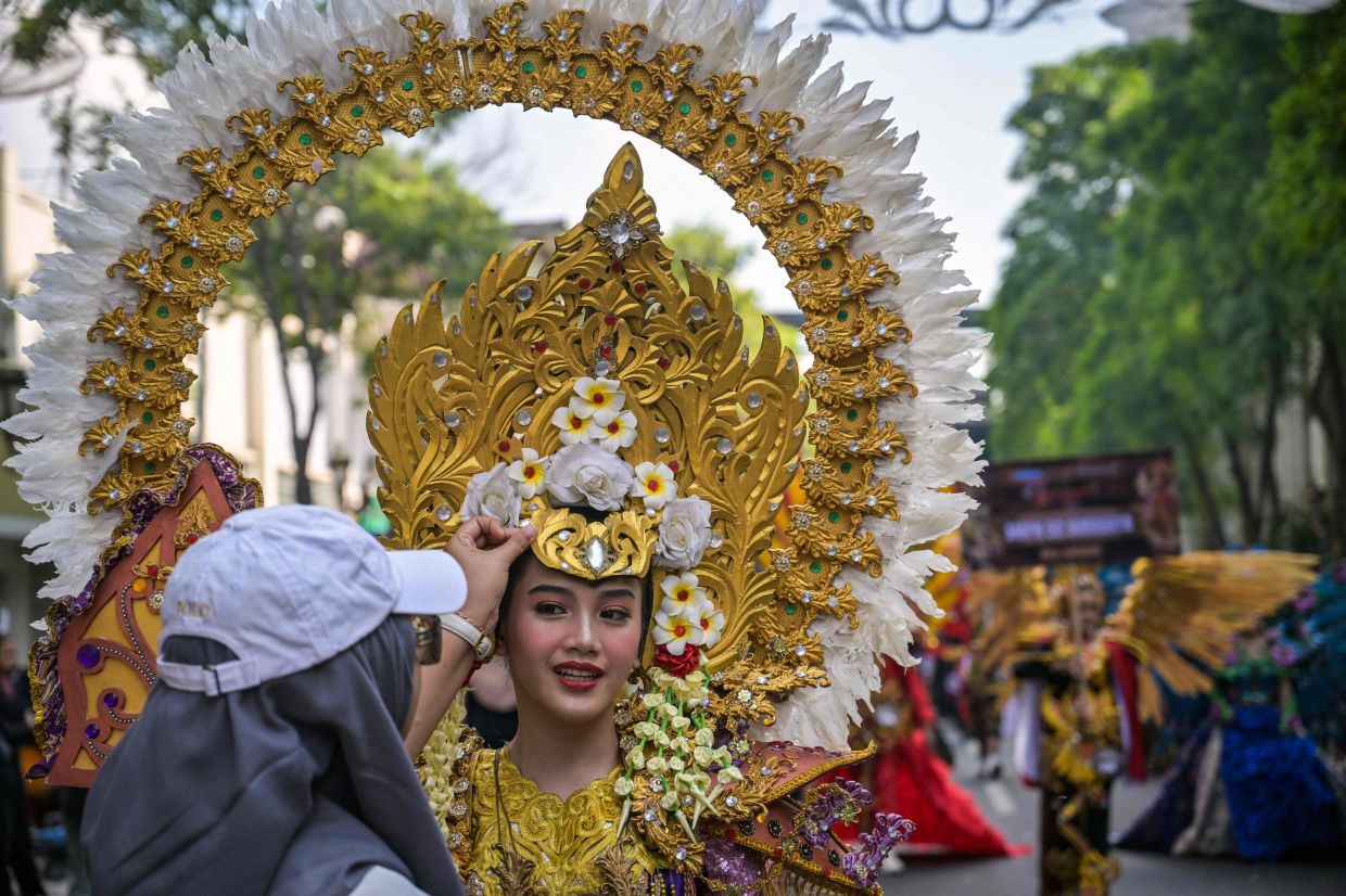 A woman adjusts her daughter's costume during the Surabaya Fashion Festival along a street in Surabaya on Sunday, June 21, 2026.-- Photo by JUNI KRISWANTO / AFP
