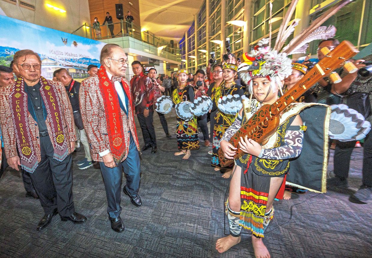 Traditional greeting: Anwar and Abang Johari (left) being welcomed with a cultural performance at the state Gawai dinner in Kuching. — ZULAZHAR SHEBLEE/The Star