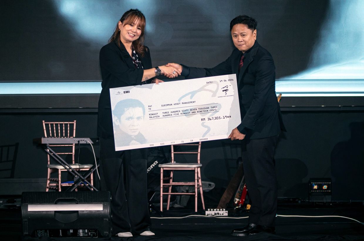Kim Lim (left) presenting a mock cheque to Atai. Photo: Bernama