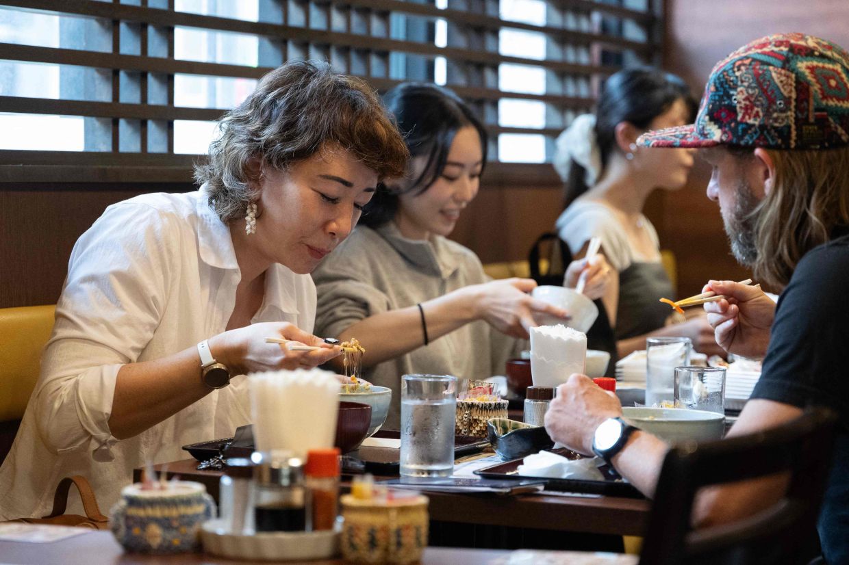 US tourist Wesley Smith (R) and his wife Maya Bourdeau eating lunch at the Natto Kobo Sendai-ya restaurant in Tokyo. - afp