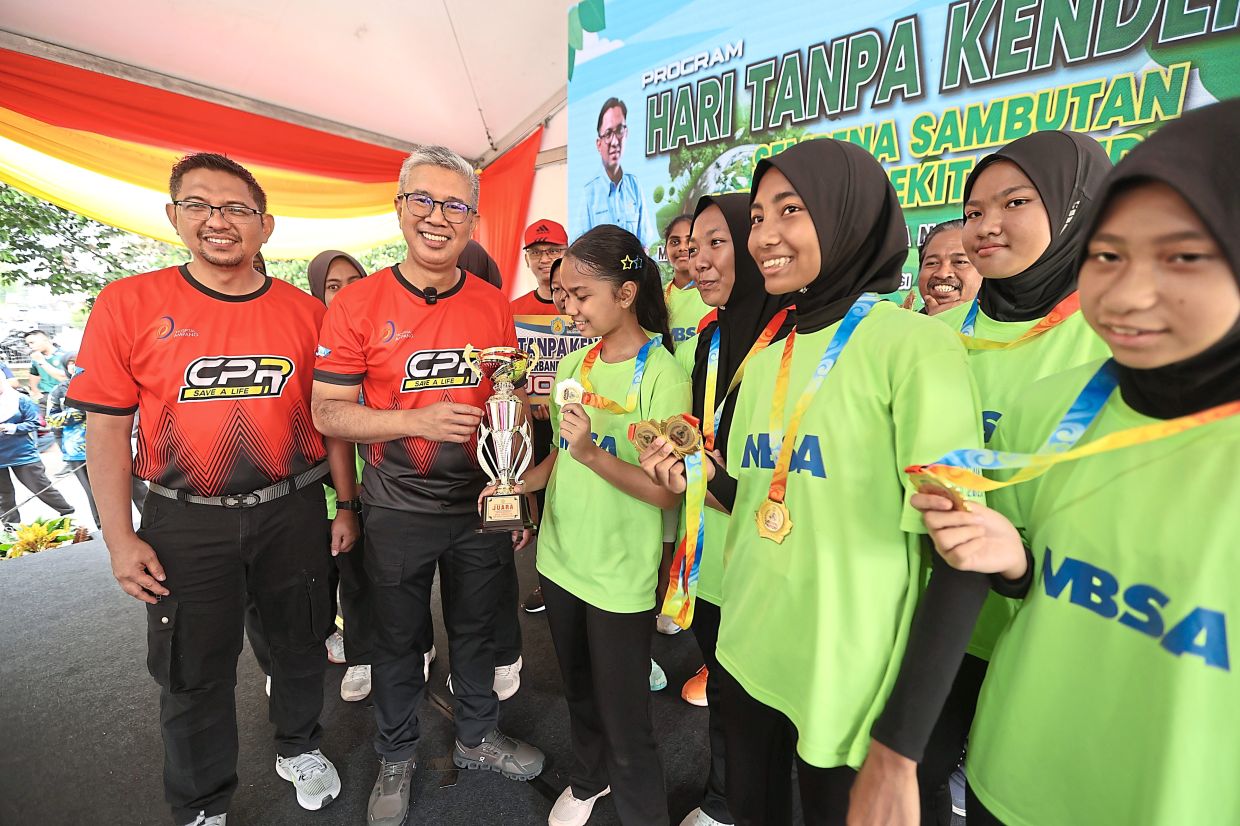 (From left) Hasrol­nizam and Tengku Zafrul during the trophy presentation to winners of a netball competition.