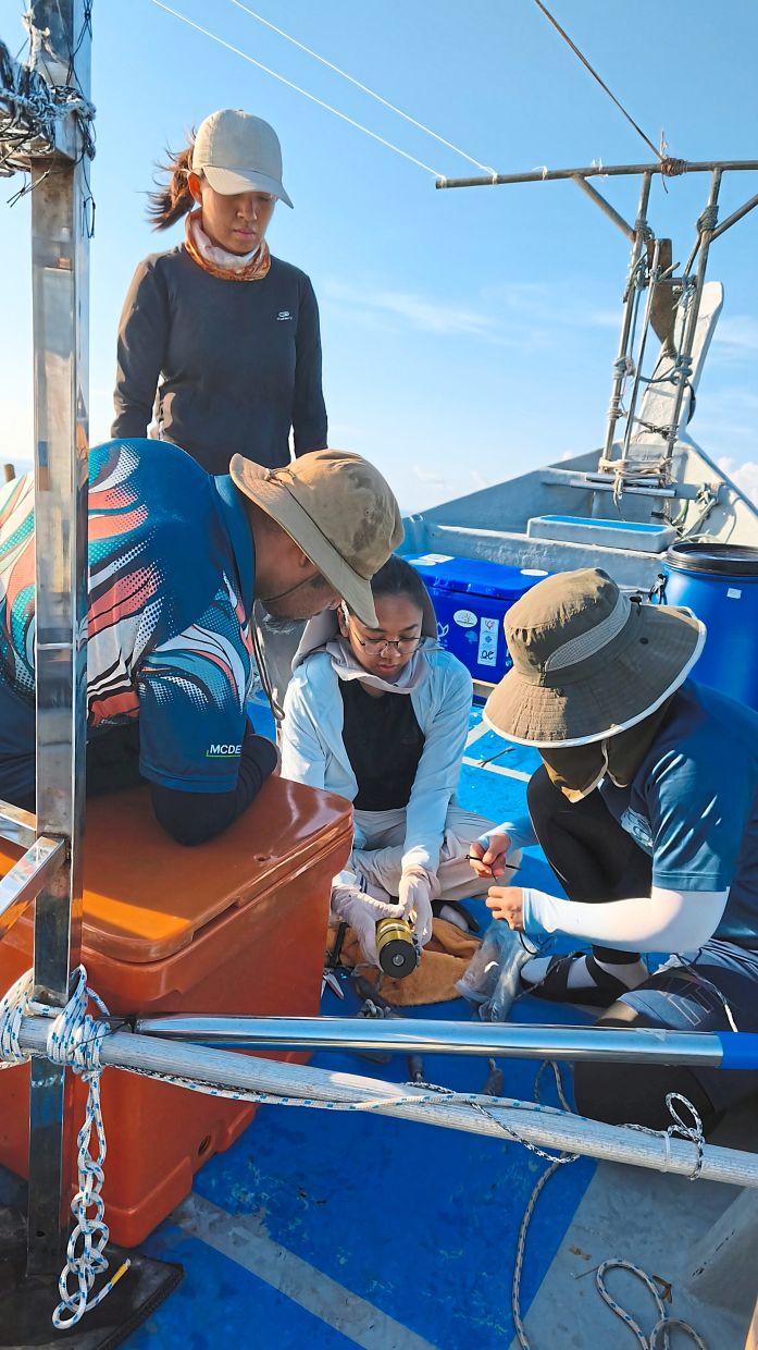 Ng (standing) and programme officer Hanna Zahirah (middle) showing volunteers how to deploy a sound trap. — ANDREA FILMER/The Star