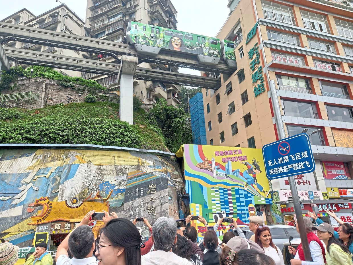Visitors outside the Liziba train station trying to capture the viral image of a train going through a residential building. — FOO YEE PING/The Star