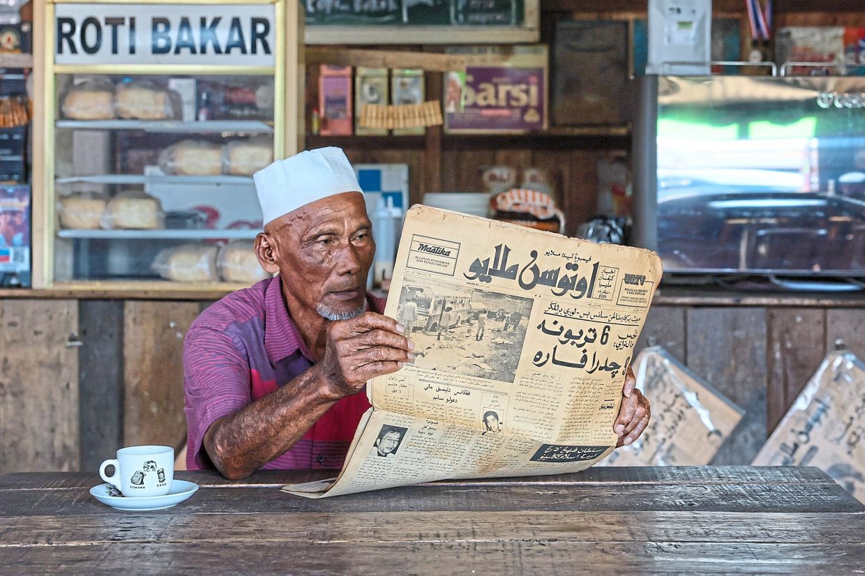 Awang Draman, 72, reliving the good old days as he reads Utusan Melayu in Jawi at Kedai Kopi Buruk, a coffeeshop that displays antiques and curios, in Kuala Terengganu.