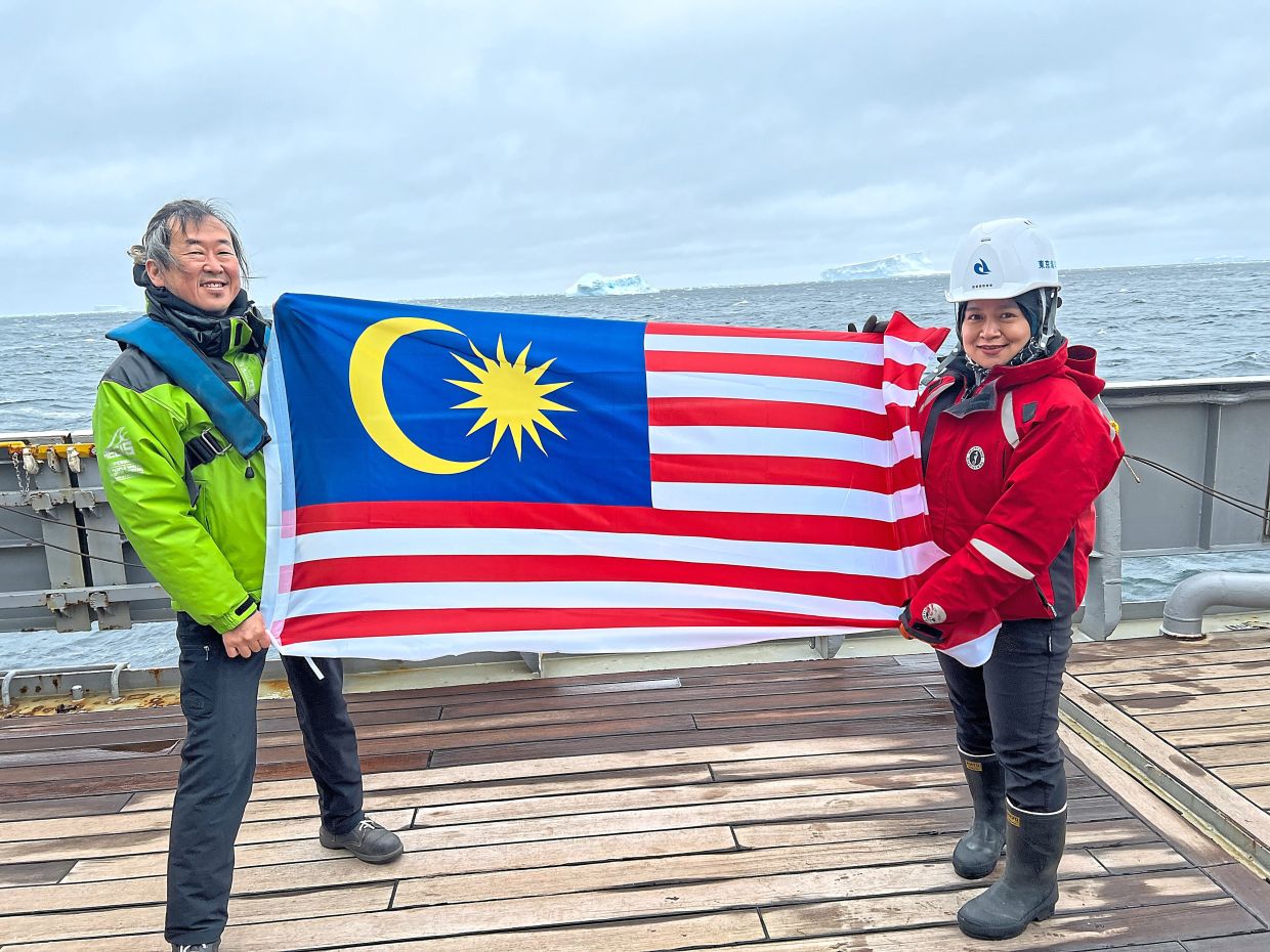 Assoc Prof Nurul Huda Ahmad Ishak (right) holding the Jalur Gemilang in Antarctica together with co-researcher Prof Dr Masato Moteki from the Tokyo University of Marine Science and Technology during the 24th Kaiyodai Antarctic Research Expedition.