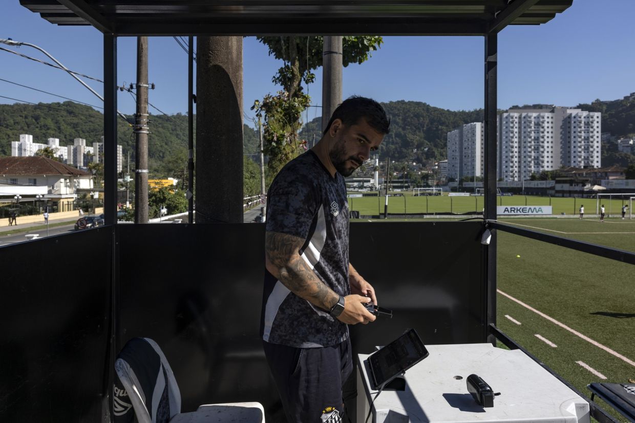 Matheus Alvarez uses a drone and an artificial intelligence-powered app to monitor players' performance during a training session at Santos FC on June 8, 2026 in Santos, Brazil.