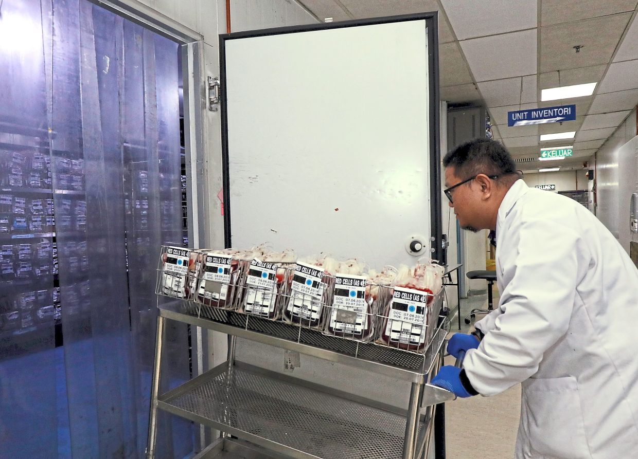 A PDN staff wheeling specific blood products into a special refrigerator.