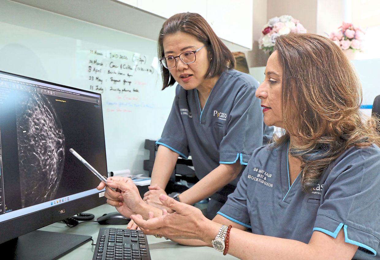 Dr Lai (standing) and Dr Harjit discussing treatment options for a breast cancer patient.