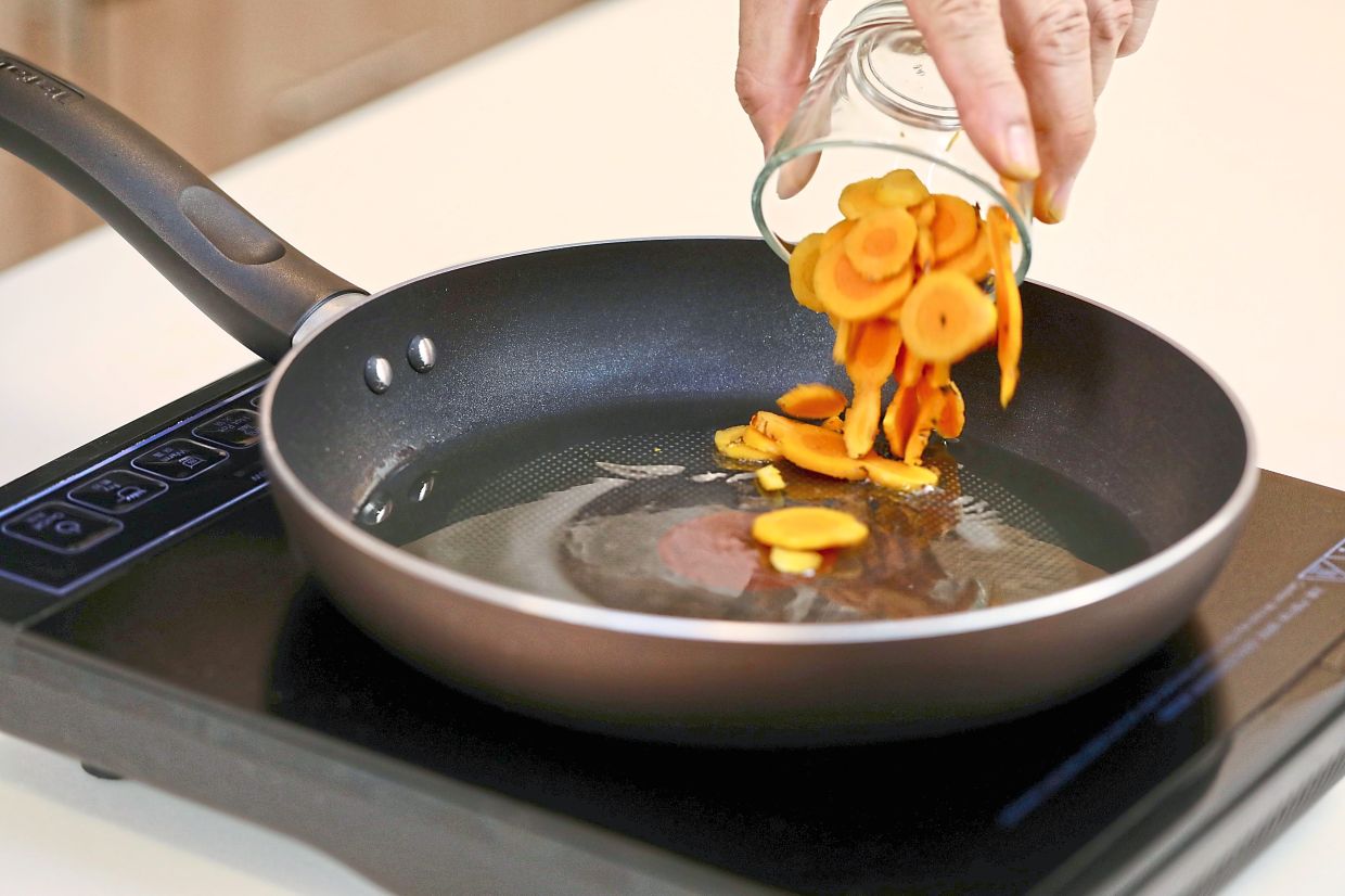 Fry the sliced turmeric until the oil turns yellow. Discard the turmeric and retain the oil for cooking the remaining ingredients.