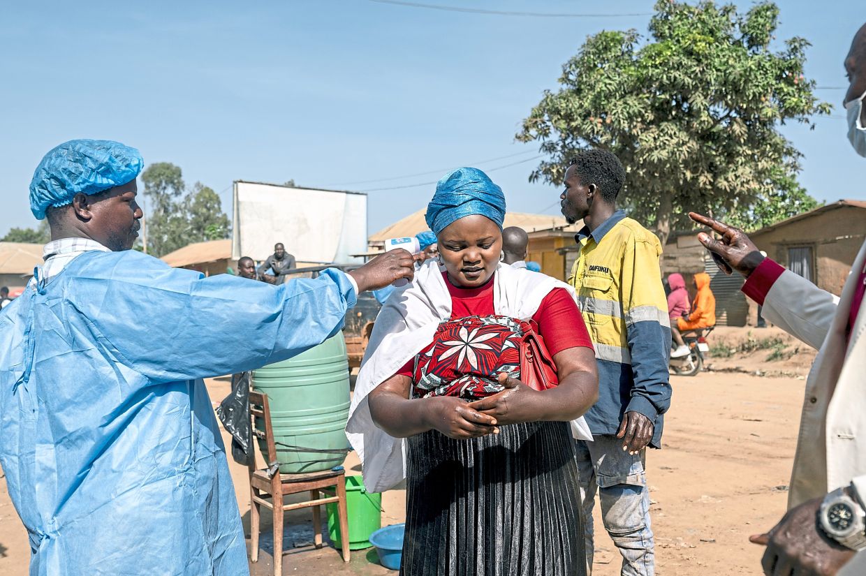 A health worker takes the temperature of a woman at a checkpoint in Bunia, as part of the response to the Ebola outbreak. The outbreak is concentrated in Ituri, the war-torn province of which Bunia is the capital. — Arlette Bashizi/The New York Times