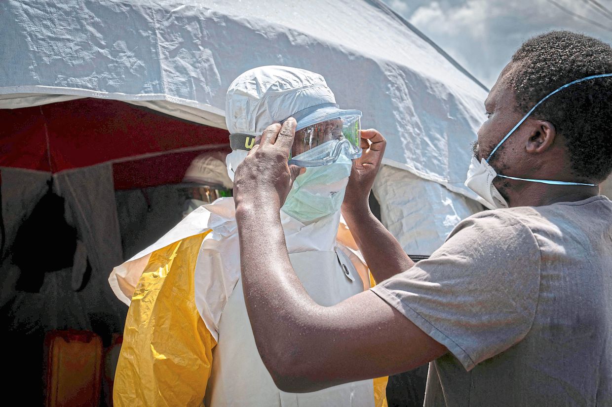 Doctors Without Borders personnel at the Elikya Clinic Ebola treatment centre are helped into personal protective equipment before entering Ebola wards in Bunia. Local health workers involved in patient care and burials face a shortage of basic protective gear. — AFP
