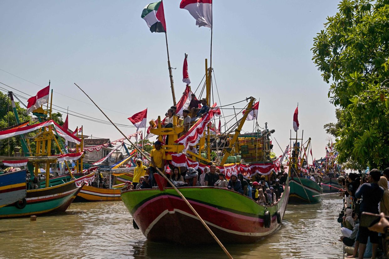 People aboard fishing boats arrive after taking part in the Petik Laut, an annual traditional Javanese thanksgiving ritual during which coastal communities express gratitude for abundant sea harvests, in Pasuruan, East Java province, on Sunday, June 28, 2026. -- Photo by Juni KRISWANTO / AFP