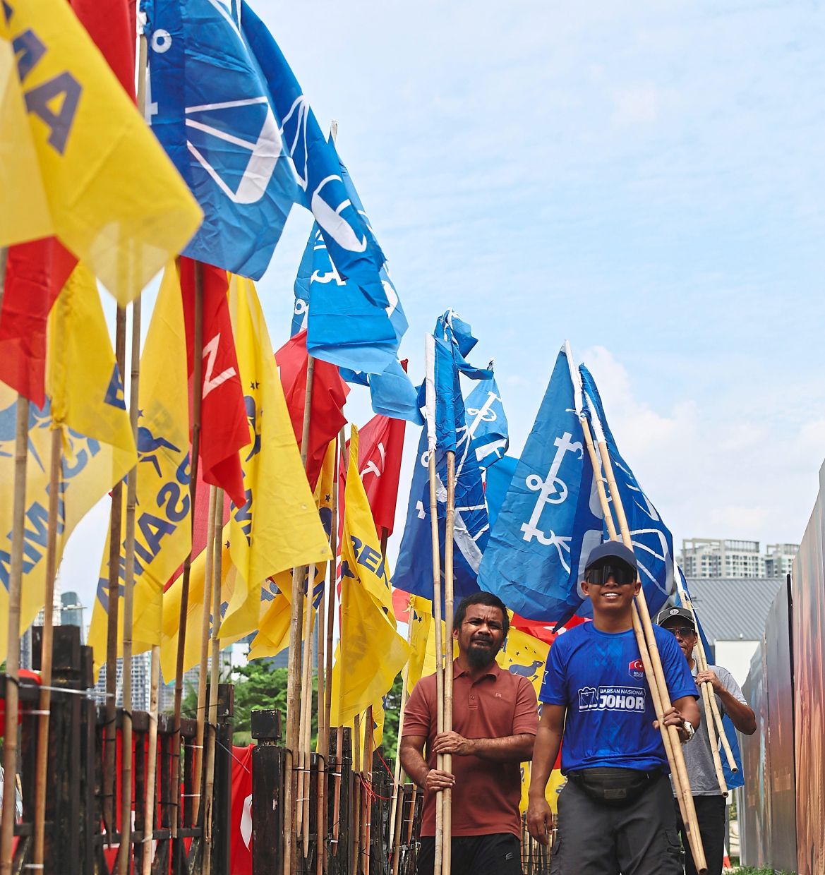Rallying the vote: Workers raising a dense thicket of campaign flags from various political parties along Jalan Kuning. — CHAN TAK KONG/The Star