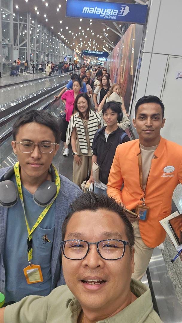 Julian (front) and Raelan (at his right) being escorted by a CARE Ambassador (in orange jacket) at KLIA. — Courtesy of Julian Wong