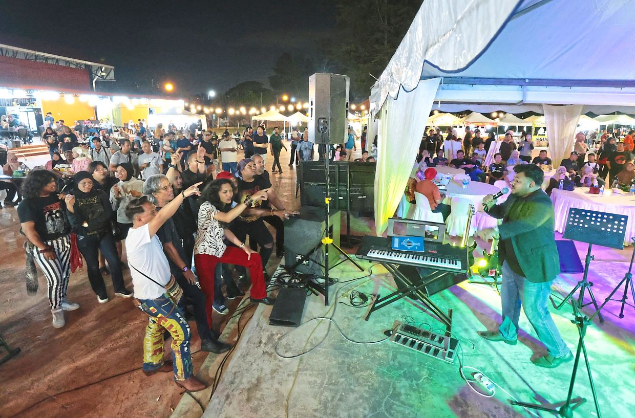 A group of music fans enjoying a rock song performance during the Penang Musicians Exhibition festival.