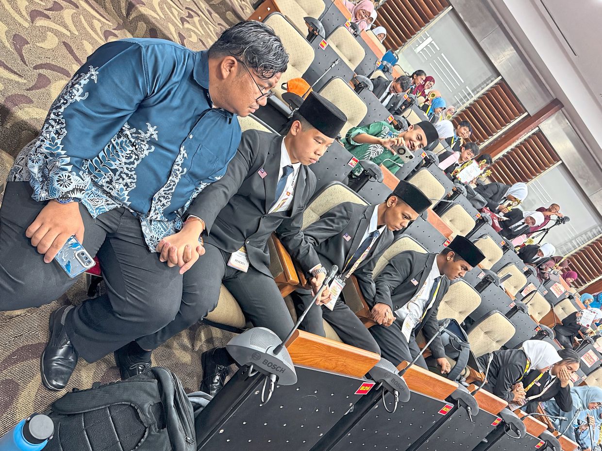 Petaling Perdana (B) team members holding hands in suspense while waiting for the results to be announced.