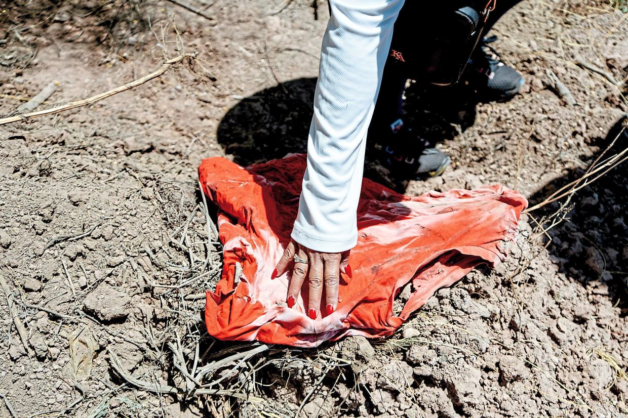 Flores examining a shirt found during a search in Juan Jose Rios. — Fred Ramos/The New York Times