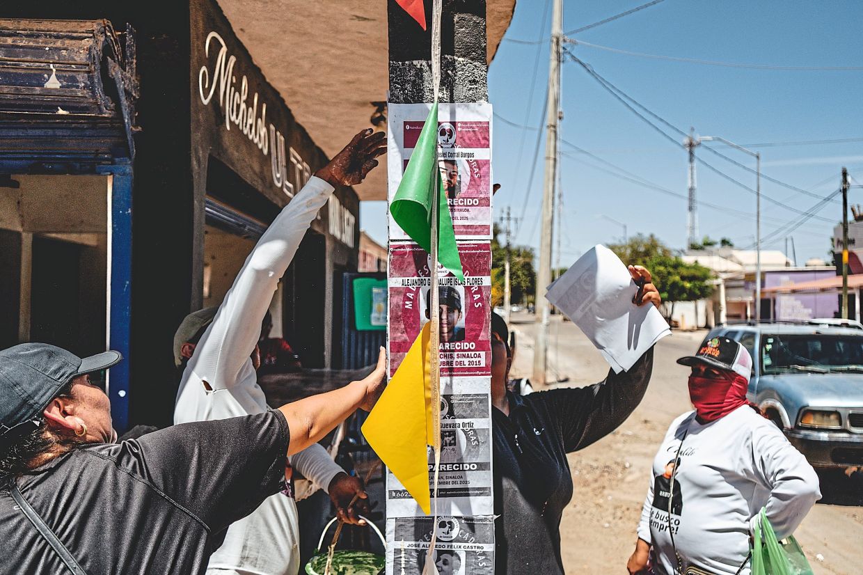 Members of a search collective posting flyers with photos of missing people in Corerepe. — Fred Ramos/The New York Times