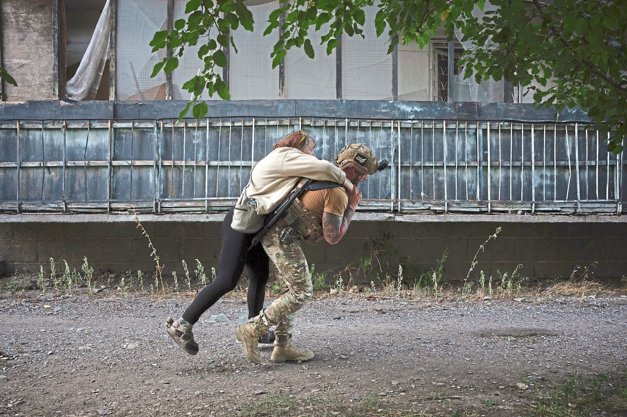 A member of a police team called the White Angels helping a resident evacuate in Kostiantynivka on Sept 16, 2025. — Tyler Hicks/The New York Times