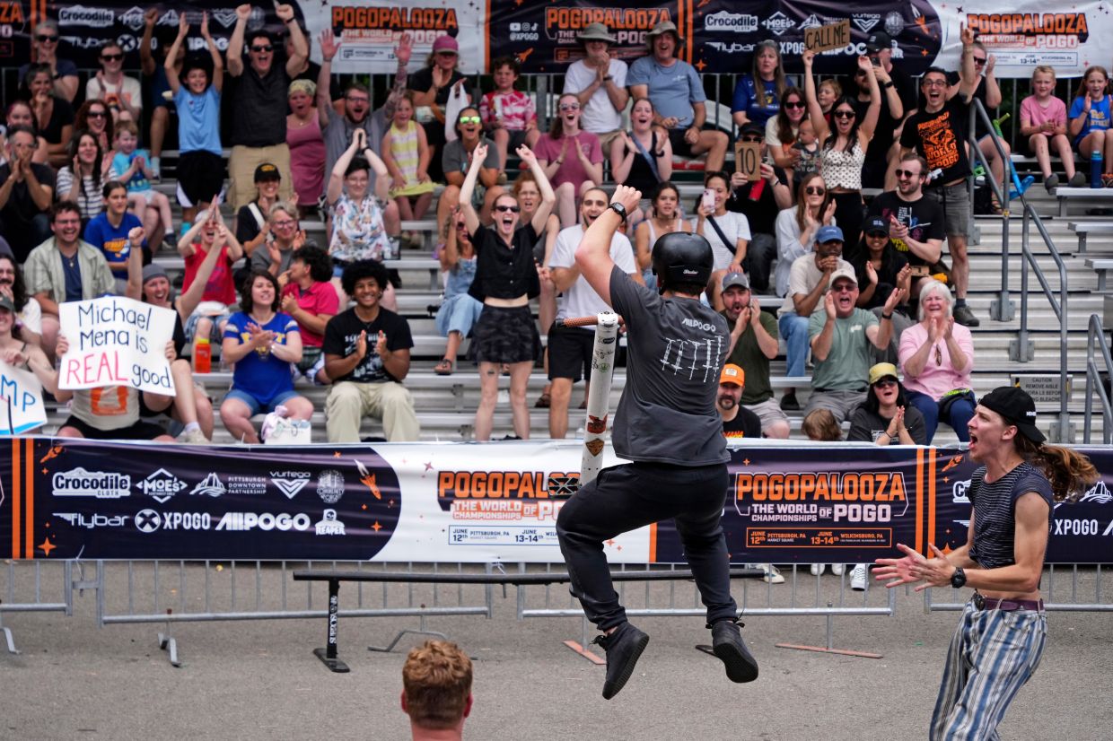 Pogo athlete Michael Mena, center, celebrates after sticking his landing after completing an award winning trick during the Best Trick competition of Pogopalooza 2026.