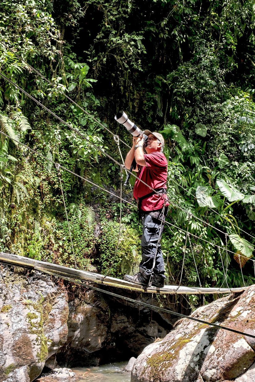 Birdwatcher Carlos Ivan Restrepo searching for birds in the Los Guacharos nature preserve in Jardin. — Esteban Vanegas/The New York Times