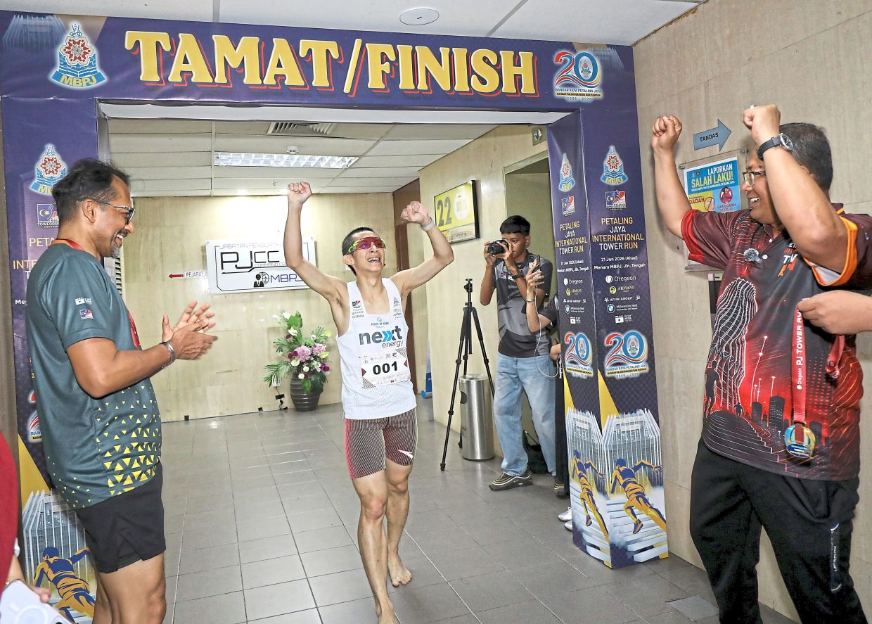 Soh arriving at the finish line while being cheered on by Mohamad Zahri (right).