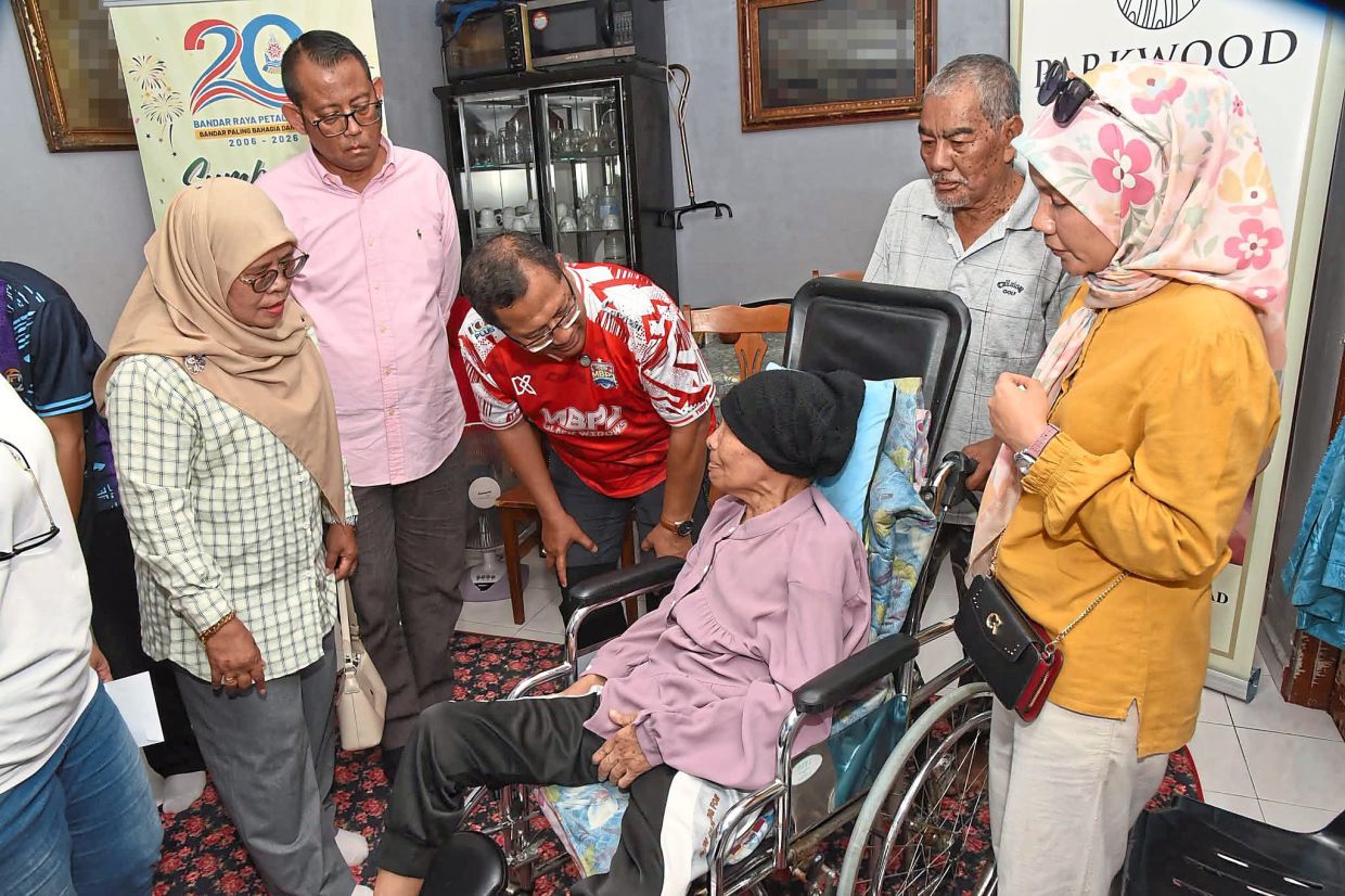 Mohamad Zahri (middle) and Taman Medan state constituency coordinator Halimey Abu Bakar (second from left) chatting with a care package recipient.