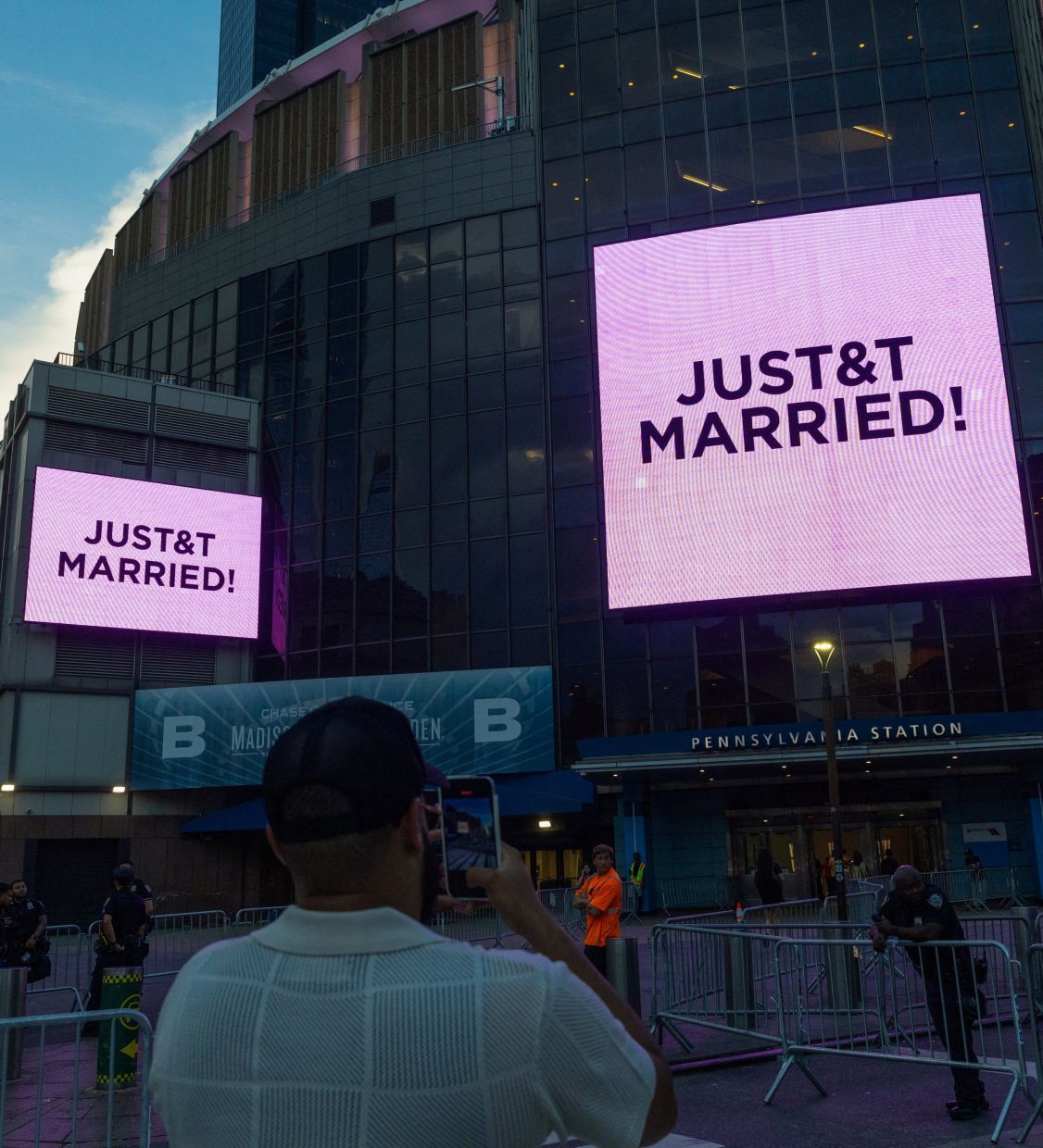 A man takes pictures of screens displaying messages referencing Taylor Swift and Travis Kelce outside Madison Square Garden, the venue for their wedding celebrations. Photo: Reuters