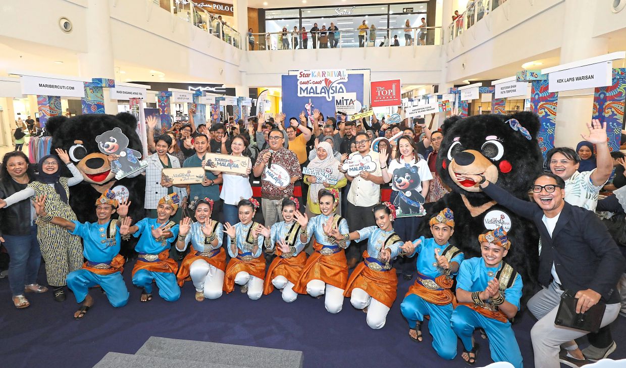 One for the memories: Star Media Group chief operating officer Lydia Wang (in white) and Mohd Roslan (on Wang’s left) taking a group photo with Visit Malaysia 2026 mascots Wira and Manja, performers and visitors at The Star Karnival Cuti-Cuti Malaysia 2026 in Kuantan. — AZLINA ABDULLAH/The Star