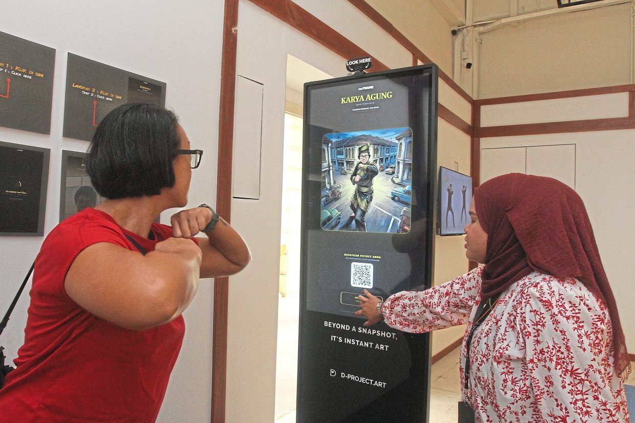 Choy Paik Lin, 47, (left) using the AI image generator at the Penang State Museum Art Gallery.