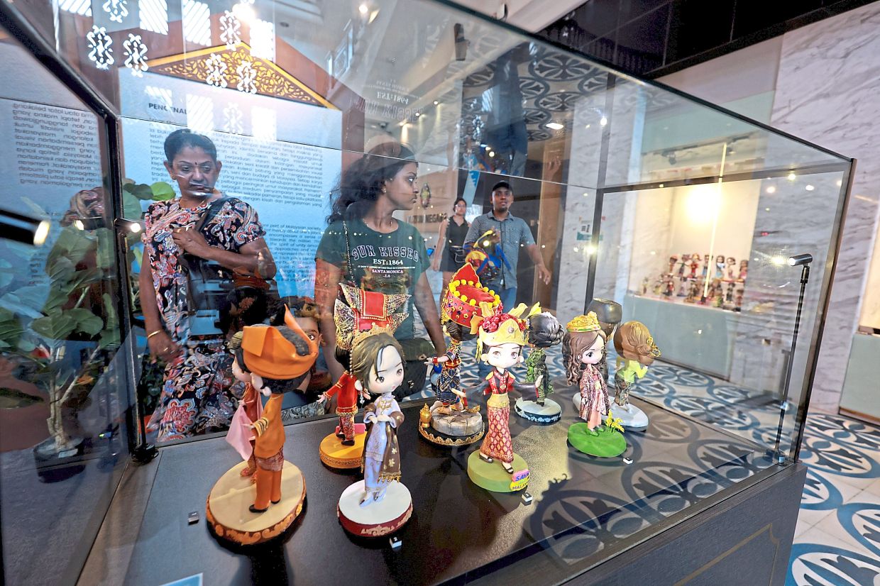 Visitors at a display of dolls wearing traditional clothes at Muzium Negara.