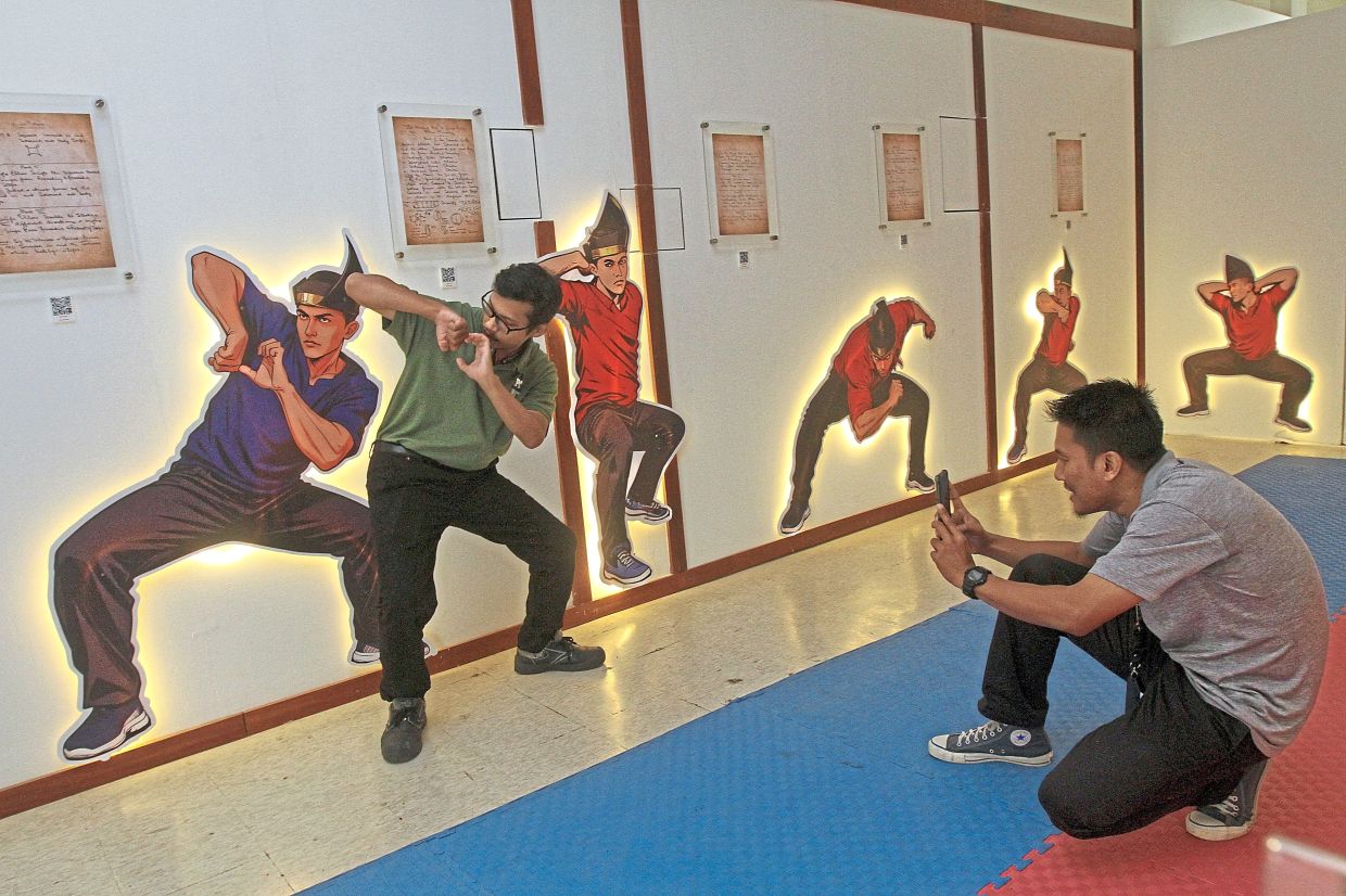 A visitor posing for a photo at the silat show display at the Penang State Museum.