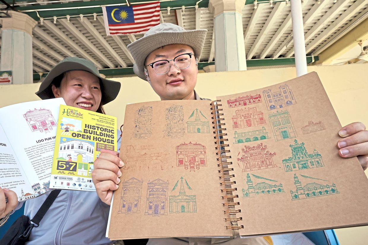Memory catchers: Wang and Zhang showing off their collection of commemorative stamps gathered during the Historic Building Open House. — CHAN BOON KAI/The Star