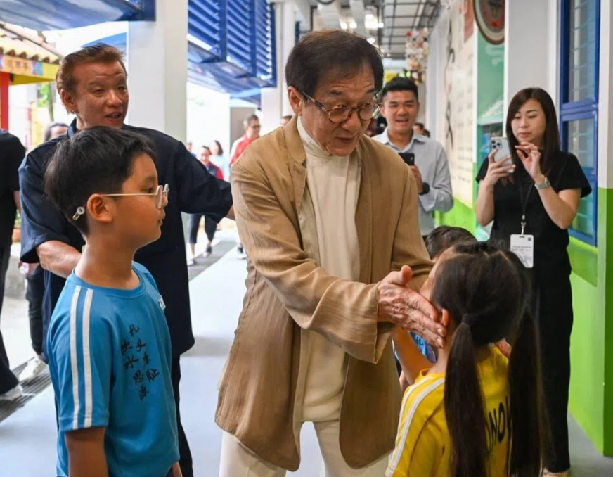 Jackie Chan interacting with pupils at Pei Chun Public School in Toa Payoh on July 7. - ST