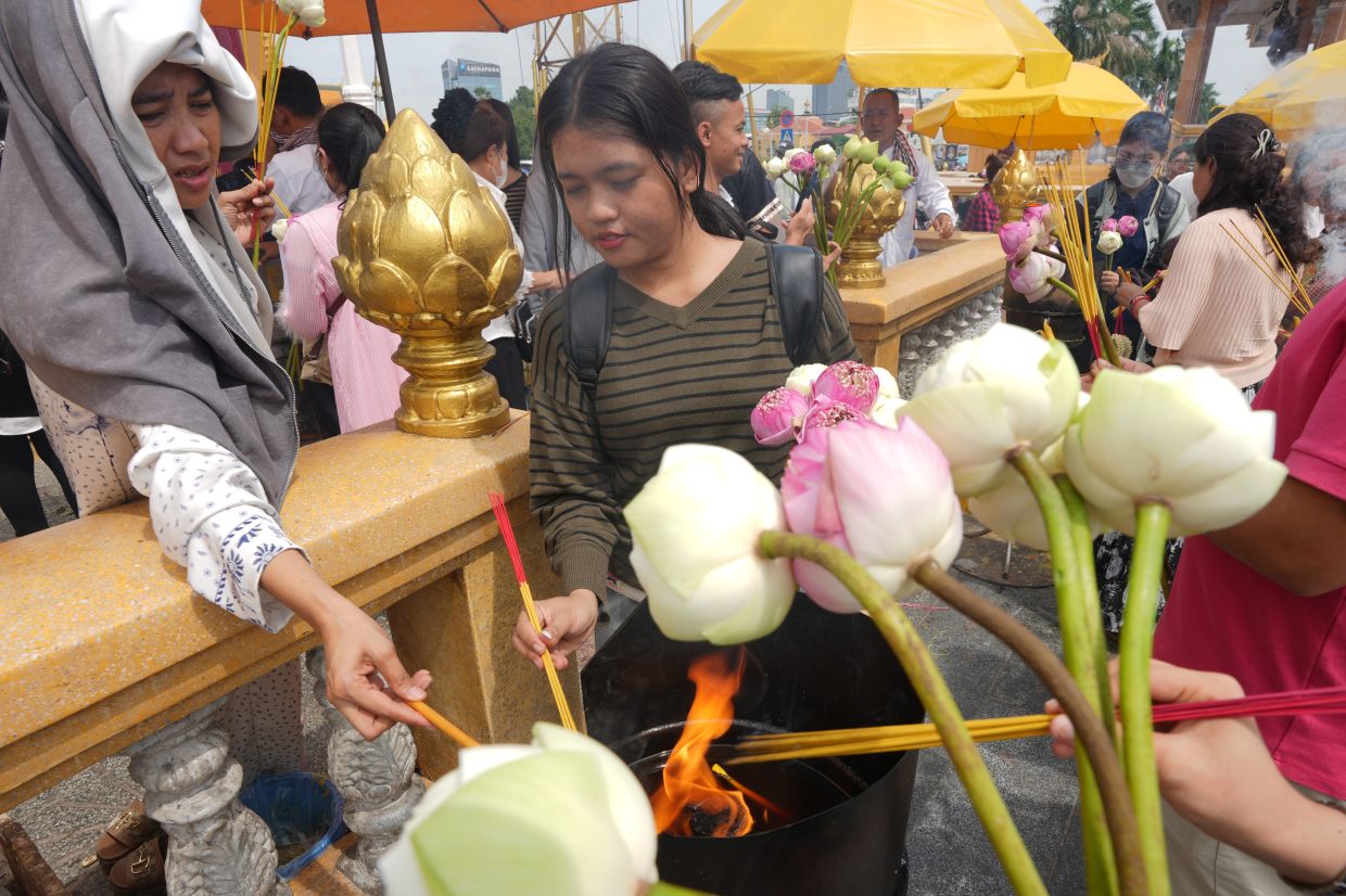 Devotees hold lotus flowers and incense sticks to offer prayers during a Buddhist holy day in Phnom Penh, Cambodia, Tuesday, on Tuesday, July 7, 2026. -- AP Photo/Heng Sinith
