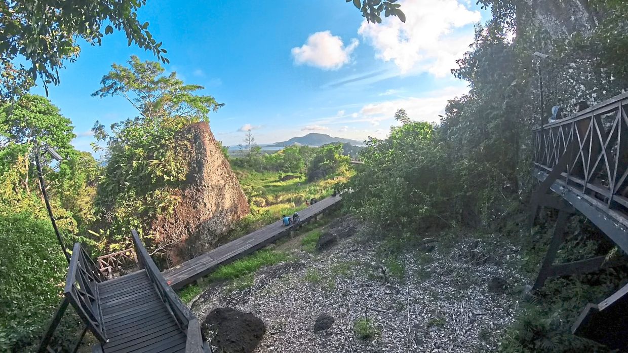 Boardwalk opening up to the grassy hilltop of Bukit Tengkorak.