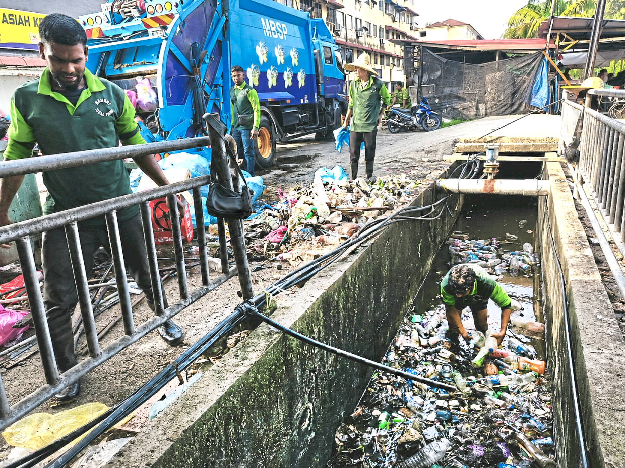 Workers clearing rubbish from a monsoon drain near a market in Butterworth. — Photos: Handout 
