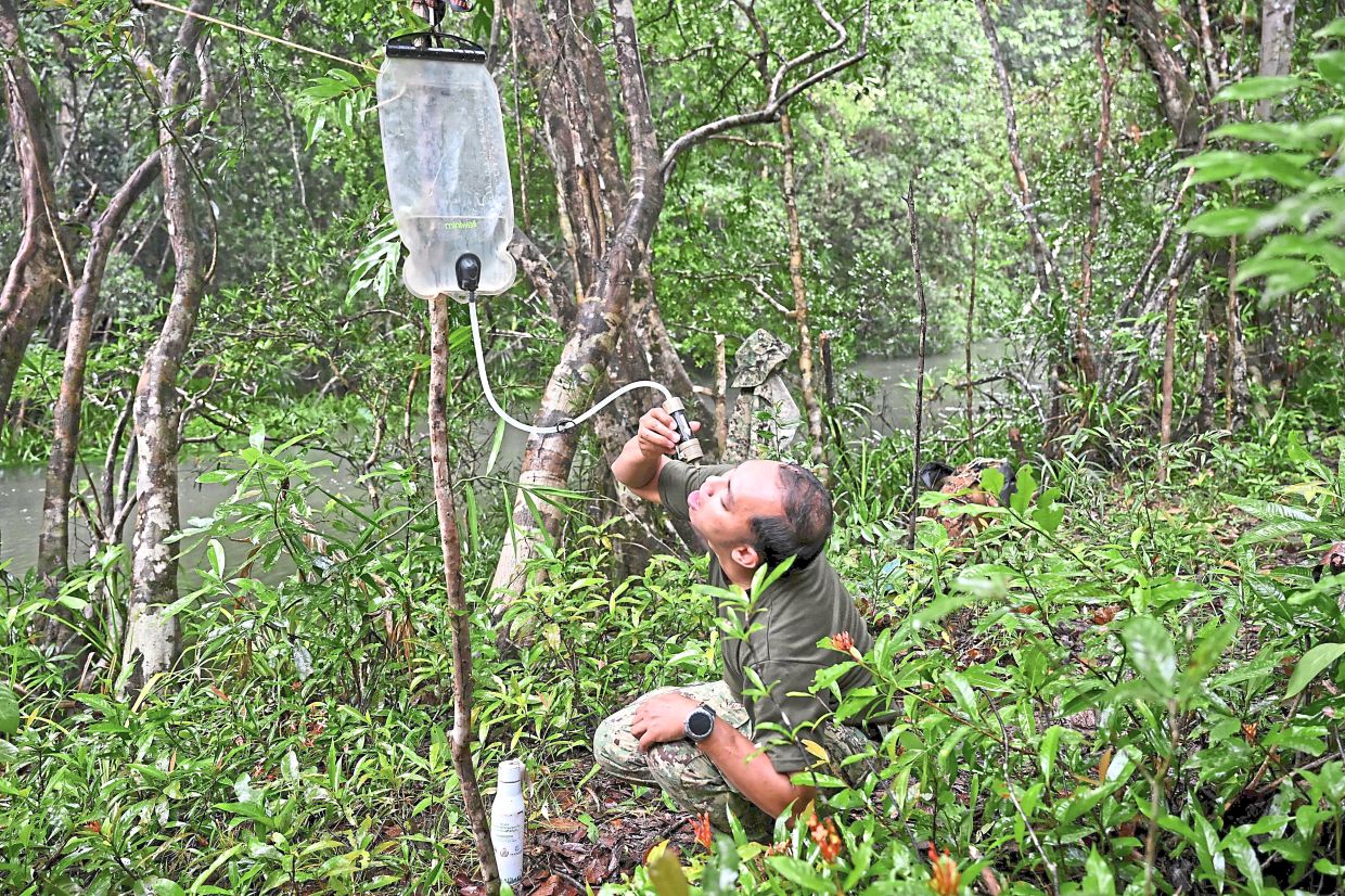 Taking a sip: (Above) A ranger drinking water from a filter. — AFP