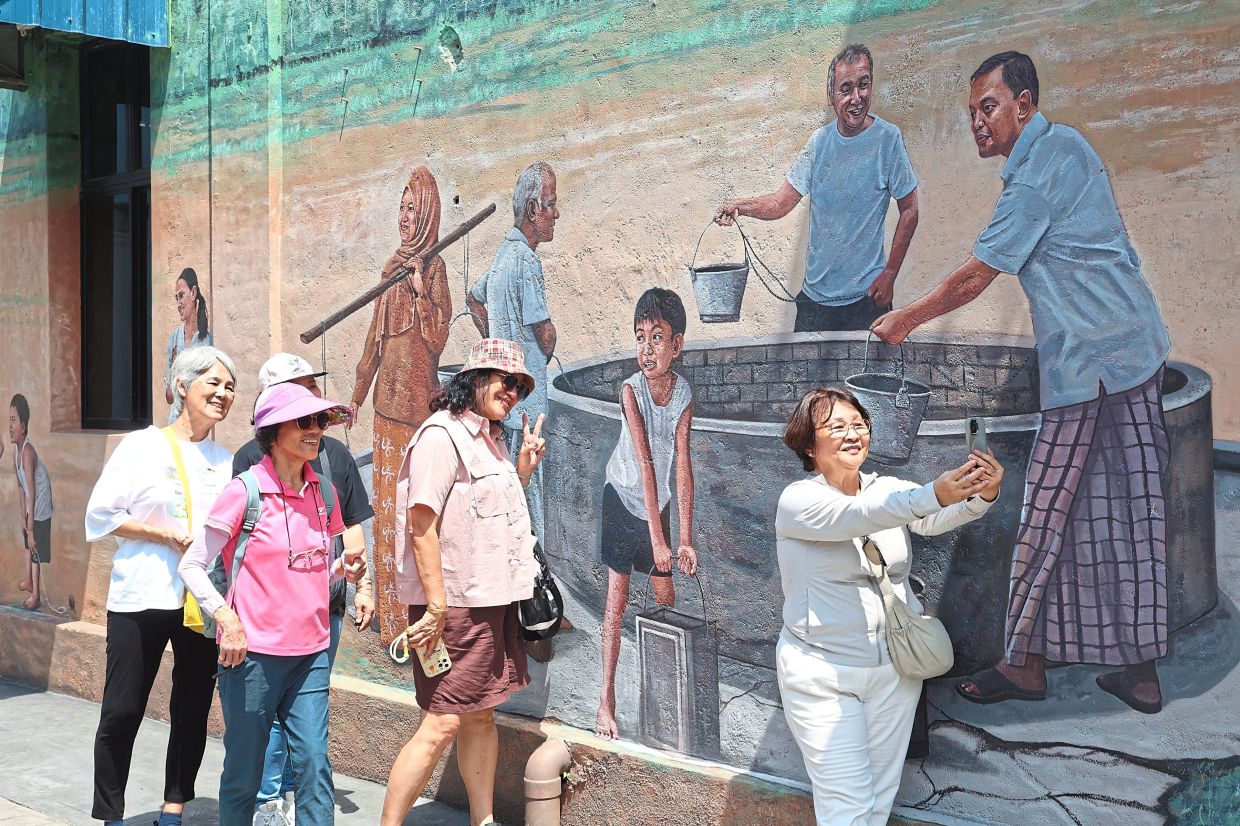 Visitors taking photos against one of the colourful murals in Paloh.