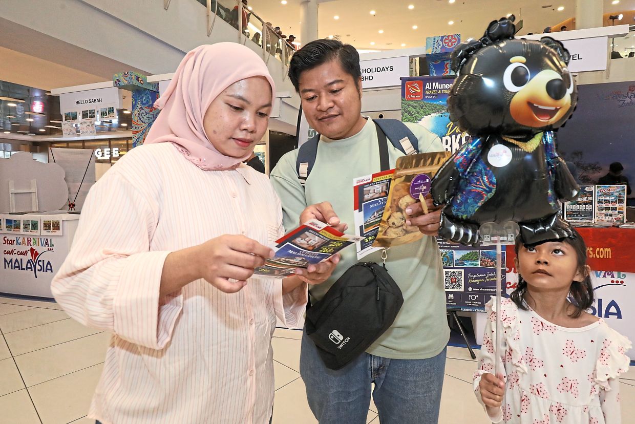Syakila, with her husband and daughter, browsing through travel brochures.
