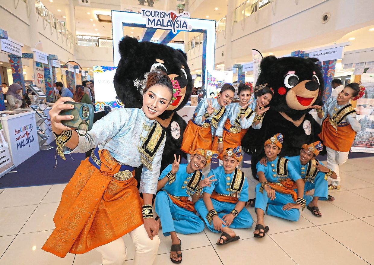 Performers posing with Wira and Manja, the Visit Malaysia 2026 mascots at the carnival.