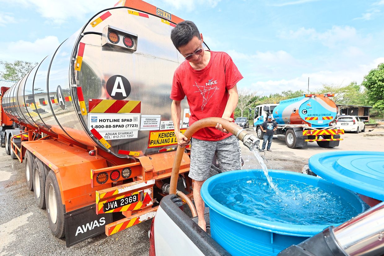 A man filling up containers with water in Pontian in February. Plunging levels at Machap Dam in February caused supply disruptions in districts such as Pontian and Kluang. — Filepic